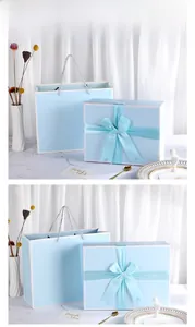 Detail of light blue gift box with silk ribbon bow and matching paper tote bag