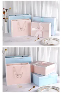 Detail of pink and blue gift boxes with silk ribbons and matching handle bags on marble
