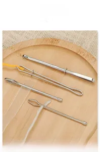 Detail of 4-piece stainless steel elastic threader set on wood tray for DIY sewing