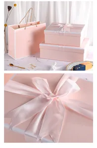 Detailed close-up of pink gift boxes with satin ribbon bows and matching paper gift bag
