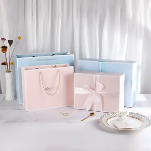 Minimalist pink and blue gift boxes with matching ribbon handles and Gift of Love text