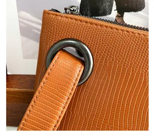 Detail view of brown lizard texture leather with gunmetal ring and zipper closure