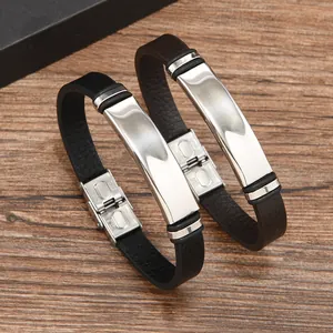 Paio di bracciali in pelle nera con piastre in acciaio inossidabile lucido su legno