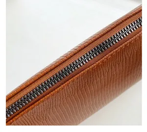 Close-up of brown faux lizard leather texture and smooth metal zipper on envelope bag