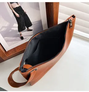 Close-up of brown textured leather envelope clutch with zipper and inner pocket detail