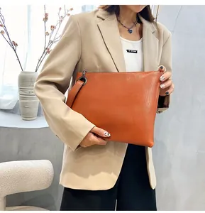 Detail of orange brown lizard skin pattern clutch with wrist strap and zipper closure