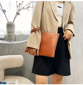 Detail of caramel brown envelope clutch with lizard pattern and matching wrist strap