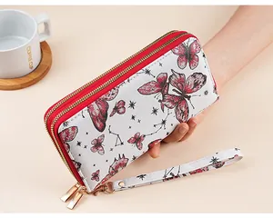 Detail of white quilted clutch wallet with red butterfly pattern and double zippers