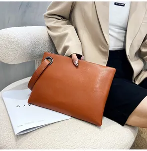 Brown envelope clutch bag with lizard texture shown with stylish beige suit outfit