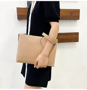Detail view of large apricot envelope clutch featuring textured crocodile pattern and wrist strap
