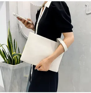 Close-up of white crocodile pattern envelope clutch bag with wristlet strap detail