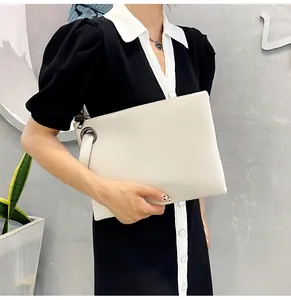 Chic beige envelope clutch bag with pebble texture and wristlet strap shown by model