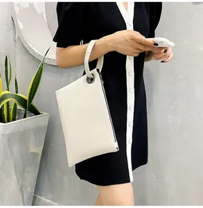 Detail view of cream white snakeskin texture clutch bag with round wristlet handle and zipper