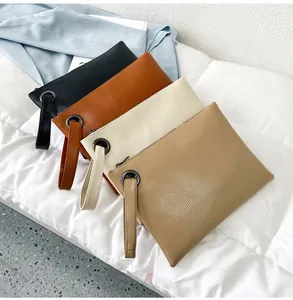 Detail of minimalist leather envelope clutch bags with metal rings and wrist straps