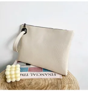 Macro detail of creamy white lizard pattern clutch with leather texture and wrist strap