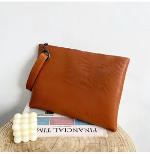Close-up of brown lizard texture clutch bag with a wrist strap and zipper closure