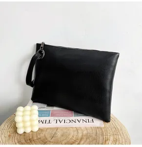 Close-up of black lizard pattern leather envelope clutch with silver zipper and wrist strap