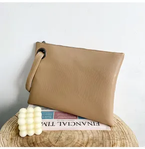 Close-up of champagne lizard texture clutch bag with metal eyelet and wrist strap