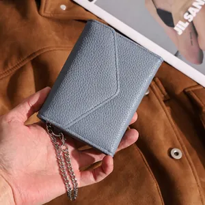 Blue-grey litchi leather envelope wallet with silver chain held in a hand