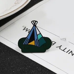 Detail of creative camping tent enamel pin with dark green base and vibrant metal texture
