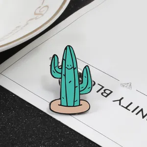 Detailed close-up of a green cactus enamel pin with a cute smiley face and butterfly clutch