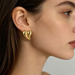 Elegant 18K gold plated heart stud earrings in polished 3D design shown on a female model