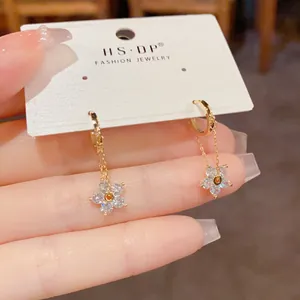 Close-up of elegant gold flower drop earrings with sparkling zircon and delicate chains