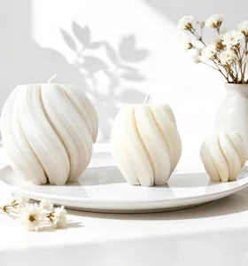 Three sizes of white spiral wave candles on a white porcelain plate with floral shadows