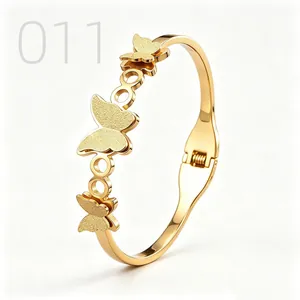 Detail of gold butterfly bangle showing sandblasted texture and hinged clasp mechanism