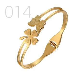 Detail of gold butterfly and clover bangle with hinged closure and polished finish