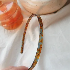 Detailed shot of thin tortoiseshell acetate headband with blue and amber mottled pattern