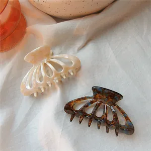 Detail view of large acetic acid hair claws in cream marble and dark tortoise shell