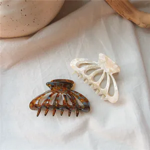Detail of tortoise shell and cream acetate hair claw clips on rustic linen background