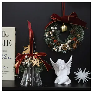 Close-up of vintage Christmas wreath with red velvet bow, gold bells and dried orange