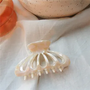 Detail of cream acetate hair claw with pearlescent finish and shell-shaped design