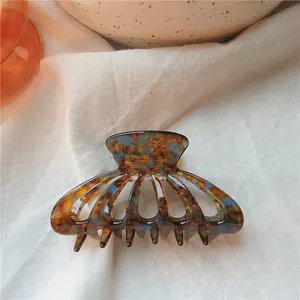 Detail view of tortoiseshell pattern claw clip on aesthetic white fabric background