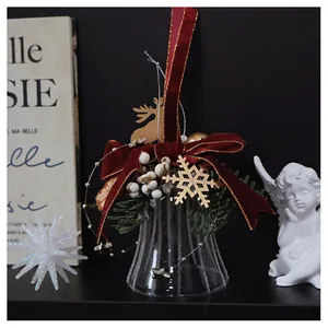 Close-up of glass Christmas bell with red velvet bow and golden reindeer decoration