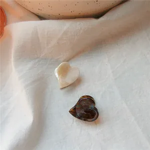 Detail view of heart-shaped tortoiseshell and cream acetate hair claws on linen fabric