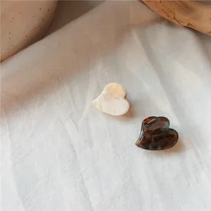 Detailed shot of heart-shaped acetate hair clips in marble white and amber tortoise shell