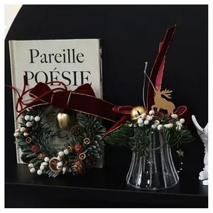 Detail of Christmas wreath with berries, pine cones and a glass bell with golden deer