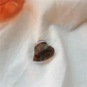 Macro shot of a heart-shaped tortoise shell acetate hair claw on a beige linen background