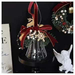 Detail of a Christmas glass bell ornament with red velvet bow and golden pine needles