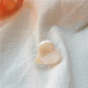 Close-up of heart-shaped cream marble acetate hair accessory with a smooth texture