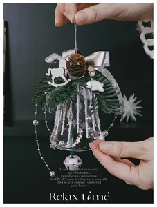 Detail of Christmas glass bell ornament featuring pine cones and a wooden rocking horse