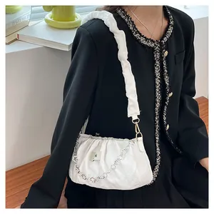 Detail of white pleated cloud bag featuring silver floral chain and soft textured fabric