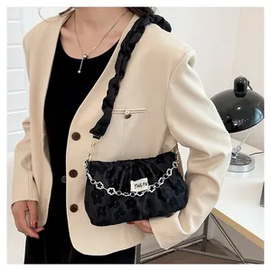 Detail of black pleated shoulder bag with floral flocking and silver flower chain