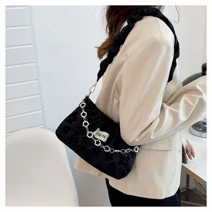 Detail of black pleated fabric bag with floral pattern and decorative flower chain strap