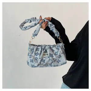 Detail of light blue floral pleated shoulder bag with silver chain and wide strap