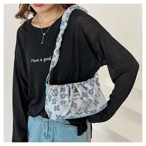 Detail view of light blue floral pleated bag with silver chain and artistic fabric strap