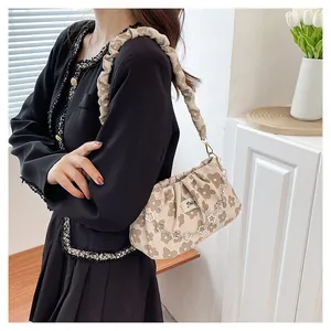 Detail of beige floral pleated shoulder bag with decorative metal flower chain strap